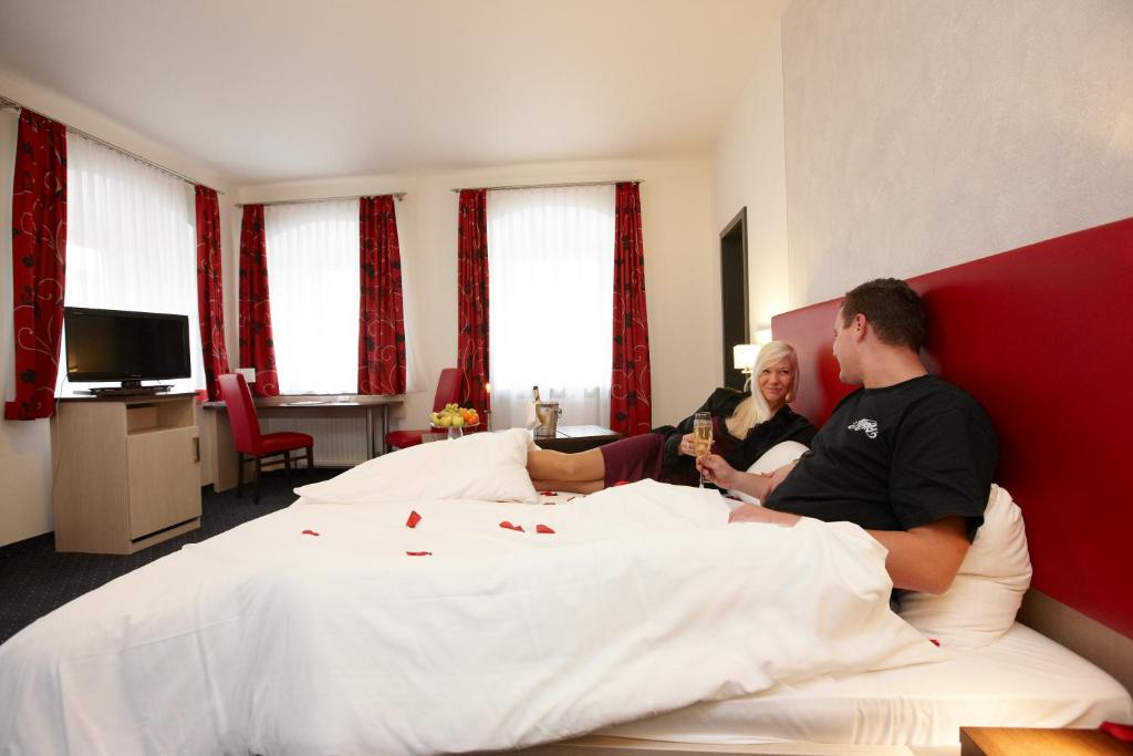 a man and a woman sitting on a bed at Hotel am Markt in Greding