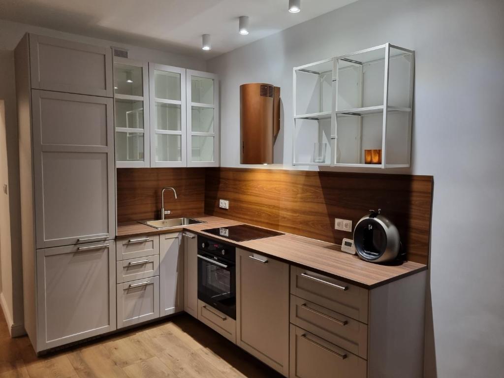 ブンツラウにあるTeatralna Nowoczesny Apartament Centrum Bolesławcaの白いキャビネットとシンクのあるキッチン