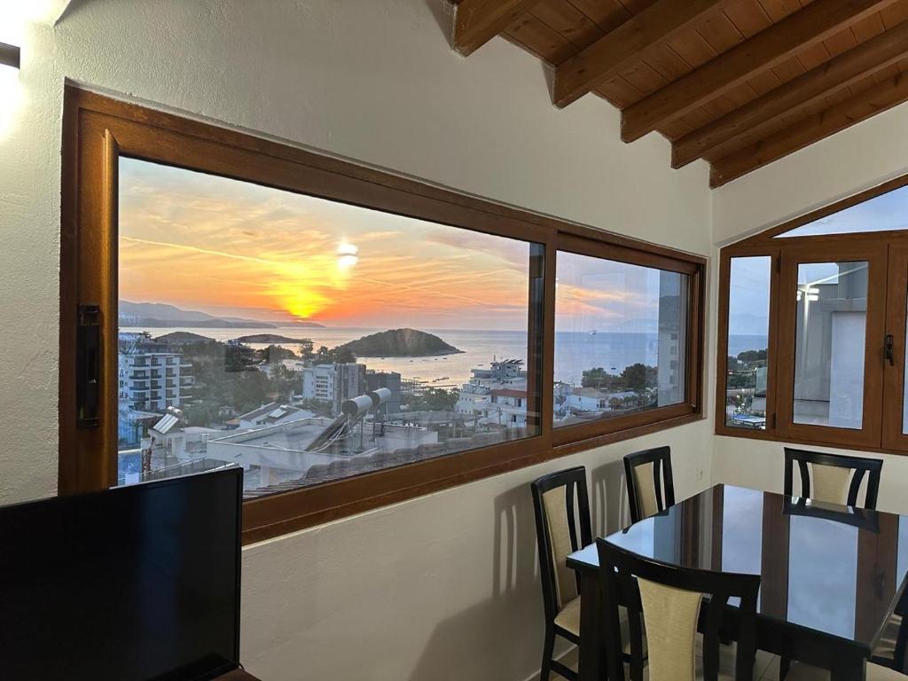 a dining room with a view of a sunset from a window at Hotel Marku in Ksamil