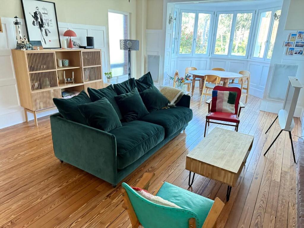 un salon avec un canapé vert et une table dans l'établissement L'Orénoque Duplex en forêt, à Le Touquet-Paris-Plage