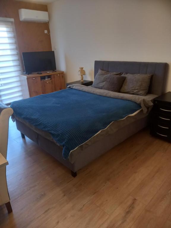 a bedroom with a large bed with a blue blanket at Apartman Ika 4N in Kraljevo