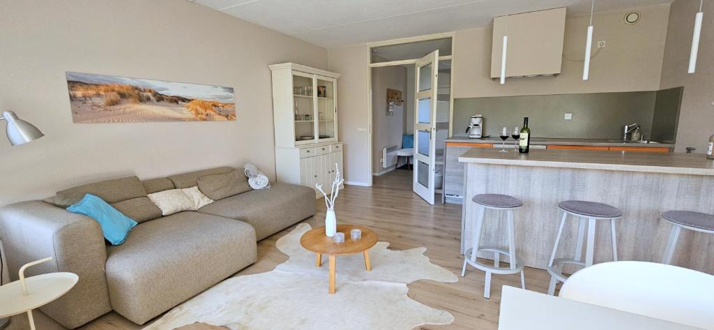a living room with a couch and a kitchen at Strandnahes Ferienhaus mit Garten hundefreundlich MeerZeit Ameland in Buren