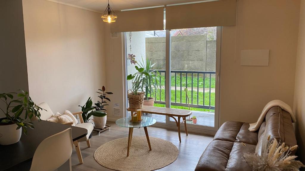 a living room with a couch and a table at Departamento cálido y espacioso con estacionamiento privado in Valdivia