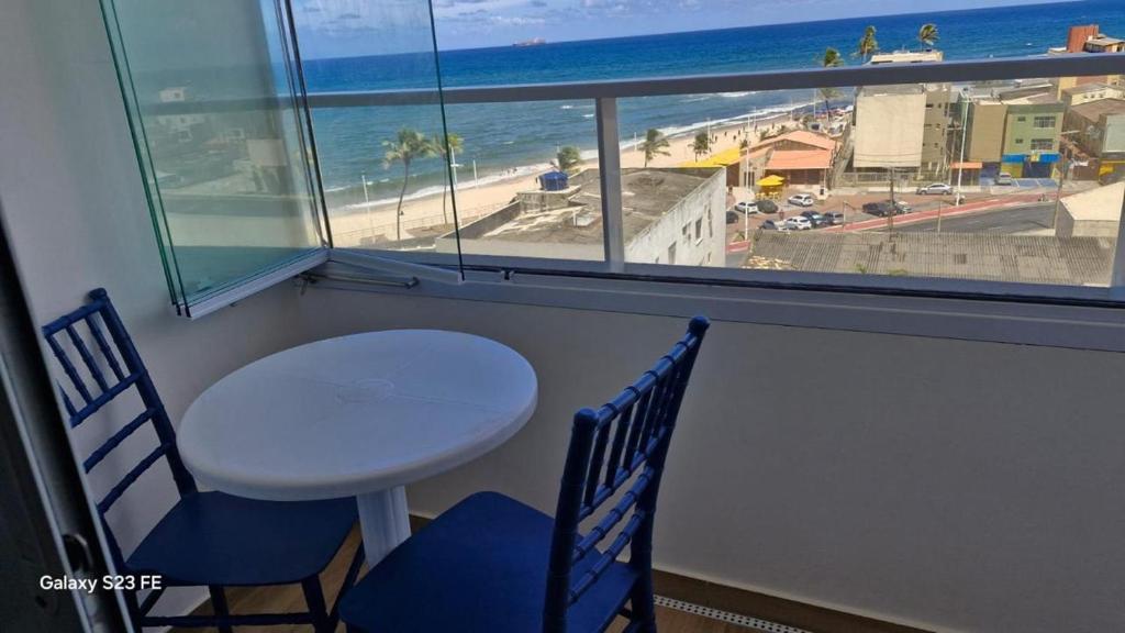 a table and chairs in a room with a view of the beach at Apt lindo e novo vista mar com garagem orla de Pituba in Salvador