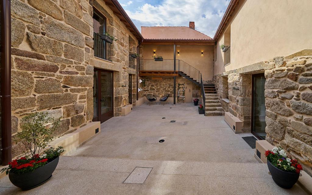 an empty courtyard of a stone building with plants at O Campiño Alojamientos Turísticos in Trasmiras