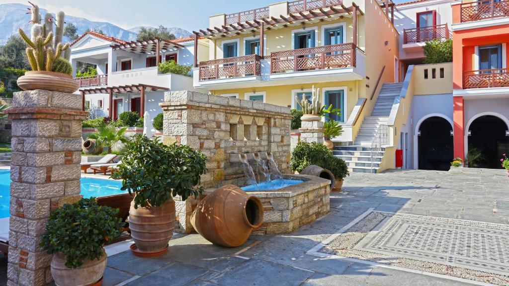 a house with a fountain in front of a pool at Sirena Residence & Spa in Marathokampos