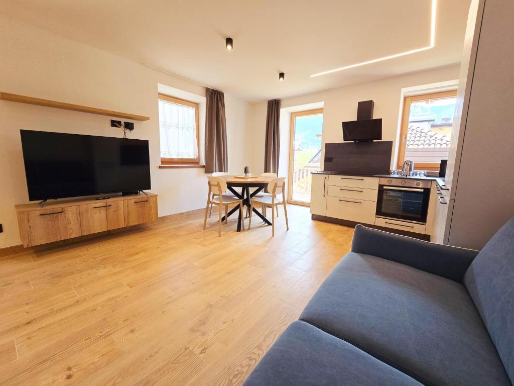a living room with a couch and a tv and a table at Alpine Lodge Tesero - Alpine Stay Apartments in Tesero