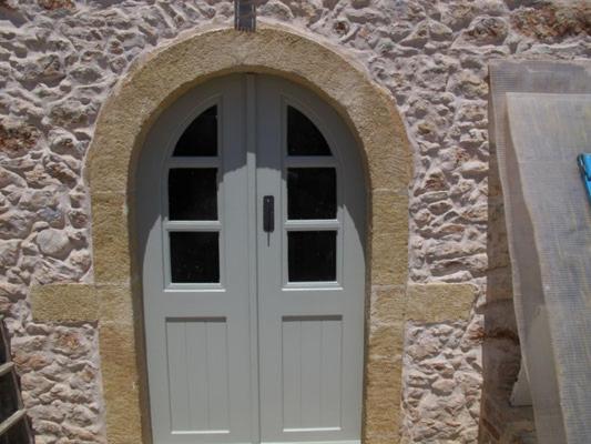 a white door in a stone building at Corones House in Frilingiánika