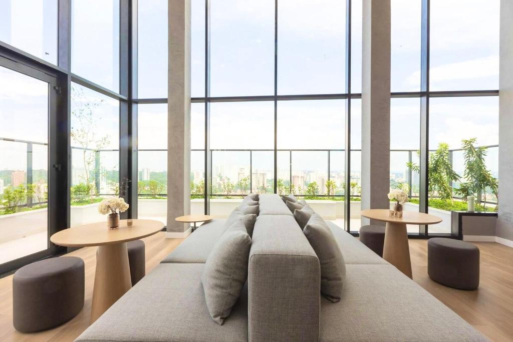 Una sala de estar con un sofá, mesas y ventanas. en Sweet Home Alto Boa Vista, en São Paulo