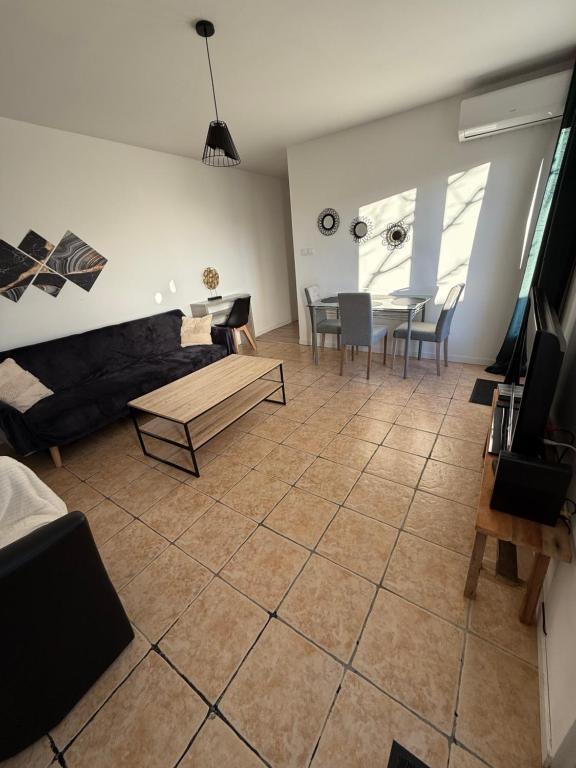 una sala de estar con un sofá y una mesa en Maison T3 avec jardin, en Narbona