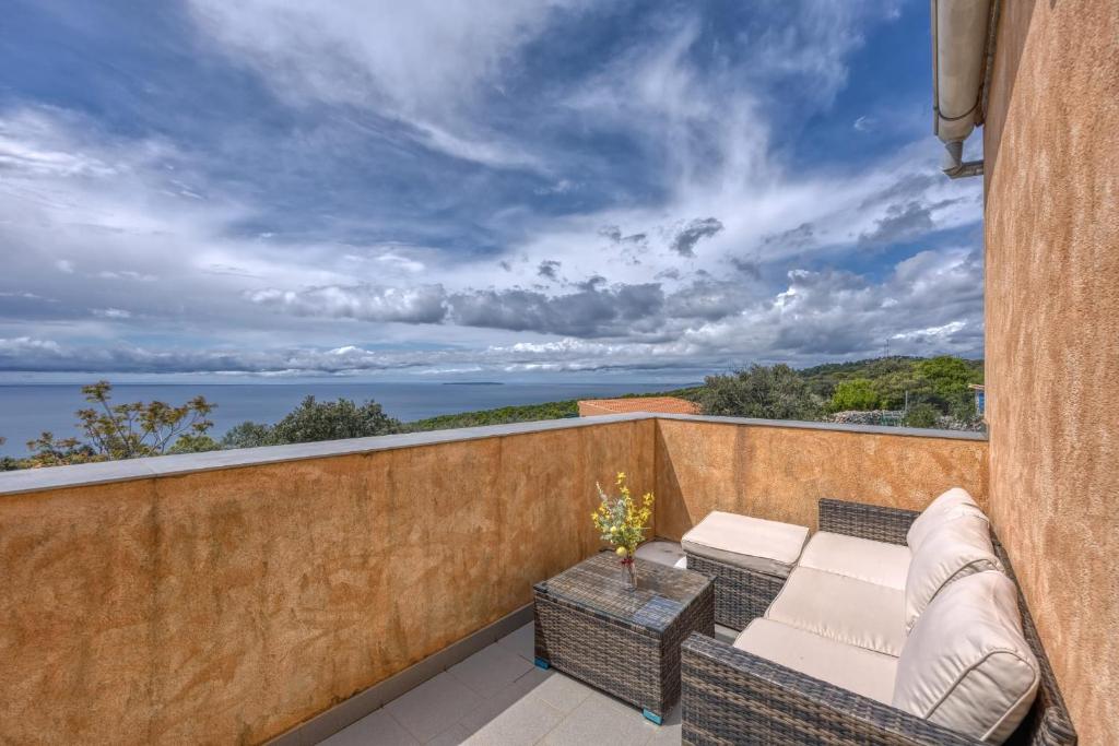 a patio with a couch and chairs on a balcony at App Bonić in Veli Lošinj