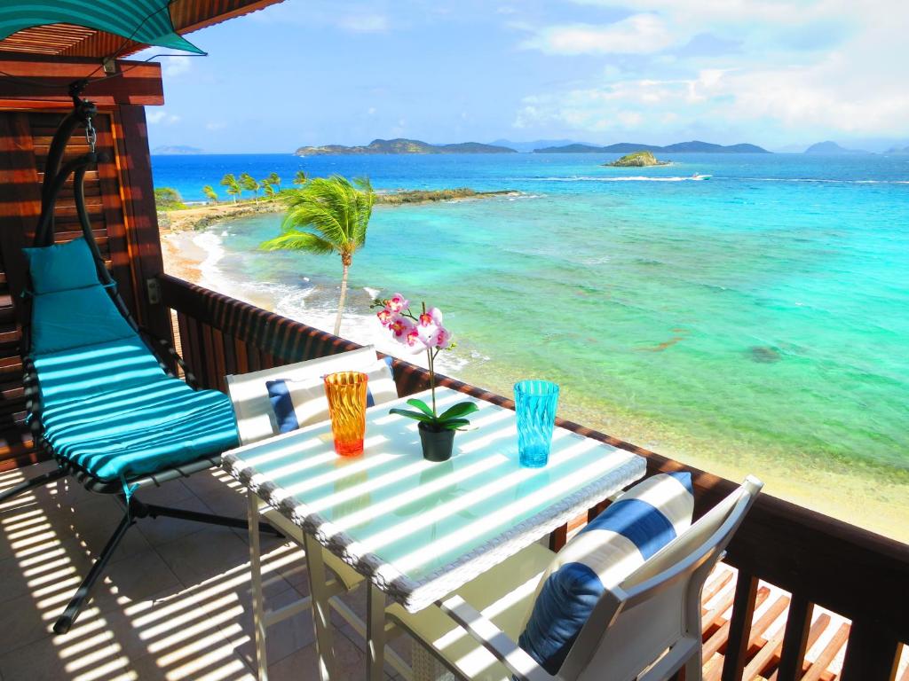 a table and chairs on a balcony overlooking the ocean at 2BR Luxury Beachfront Duplex Villa on Sapphire Beach III in East End