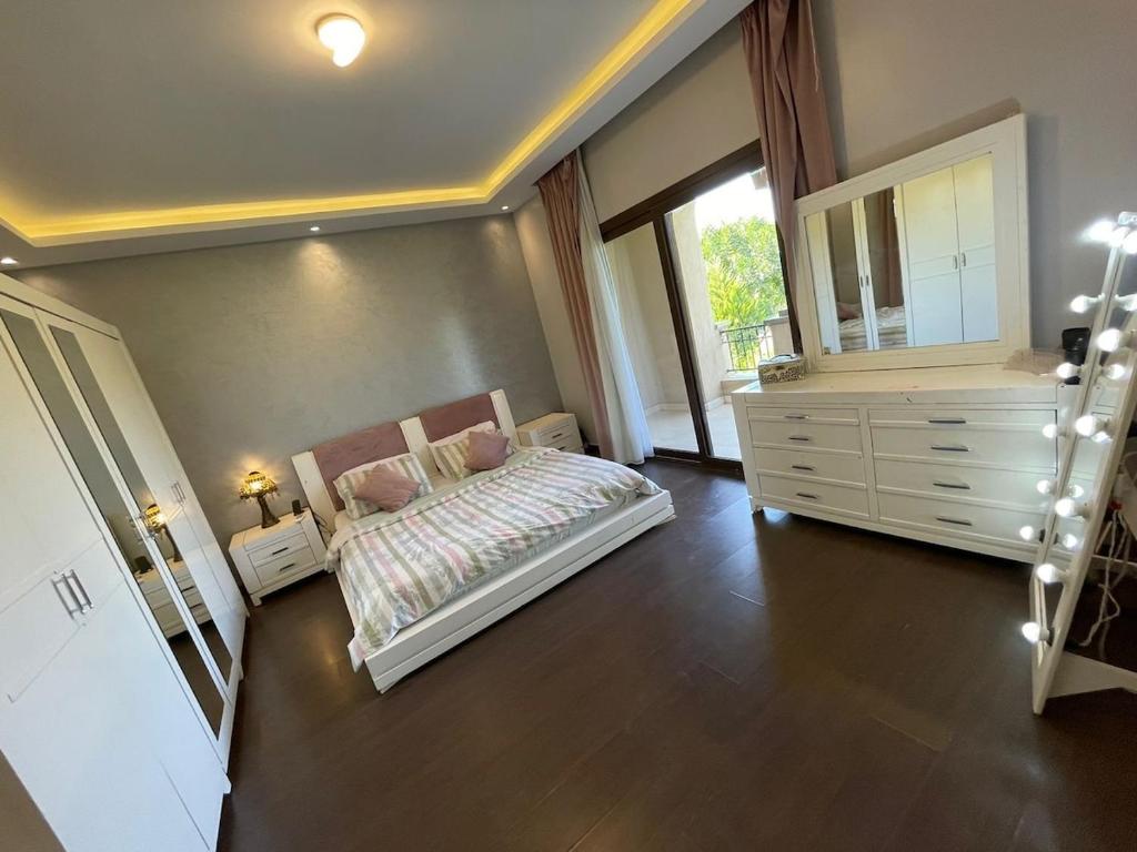 a bedroom with a bed and a dresser and a mirror at Amazing 3br Villa in Emaar - Mivida in New cairo