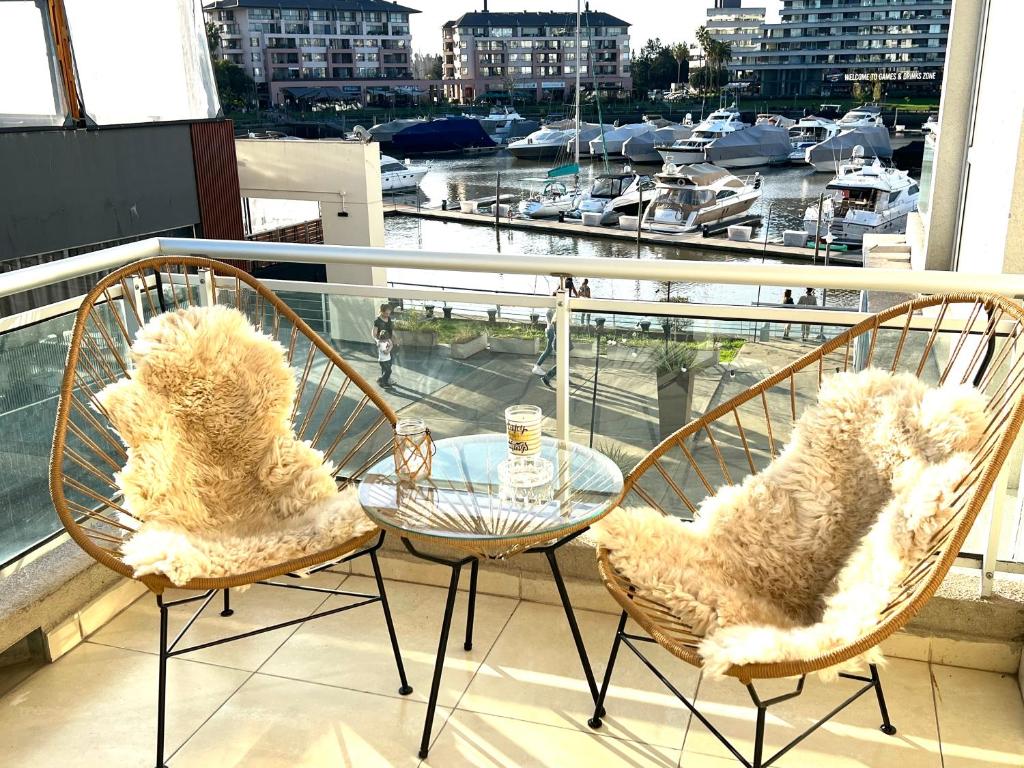 due sedie e un tavolo di vetro su un balcone con un porto di Paraíso en Nordelta, Departamento con vista soñada en Bahia Grande a Benavídez