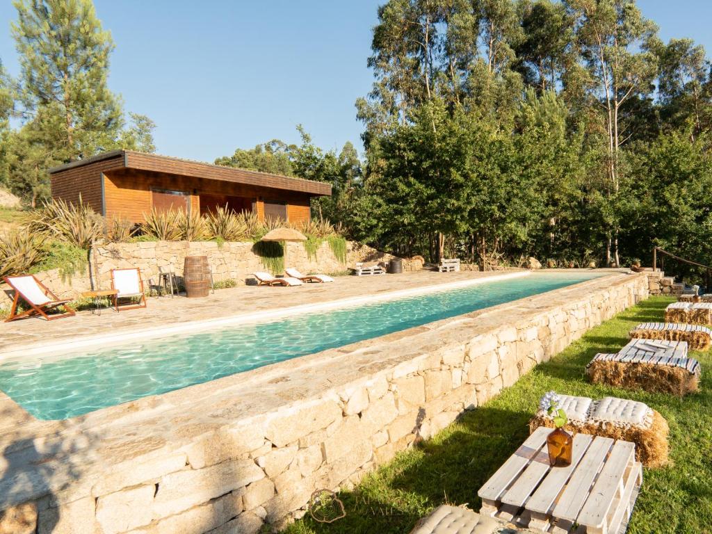 a pool with a stone wall next to a house at Tapada dos Vales in Arnoia