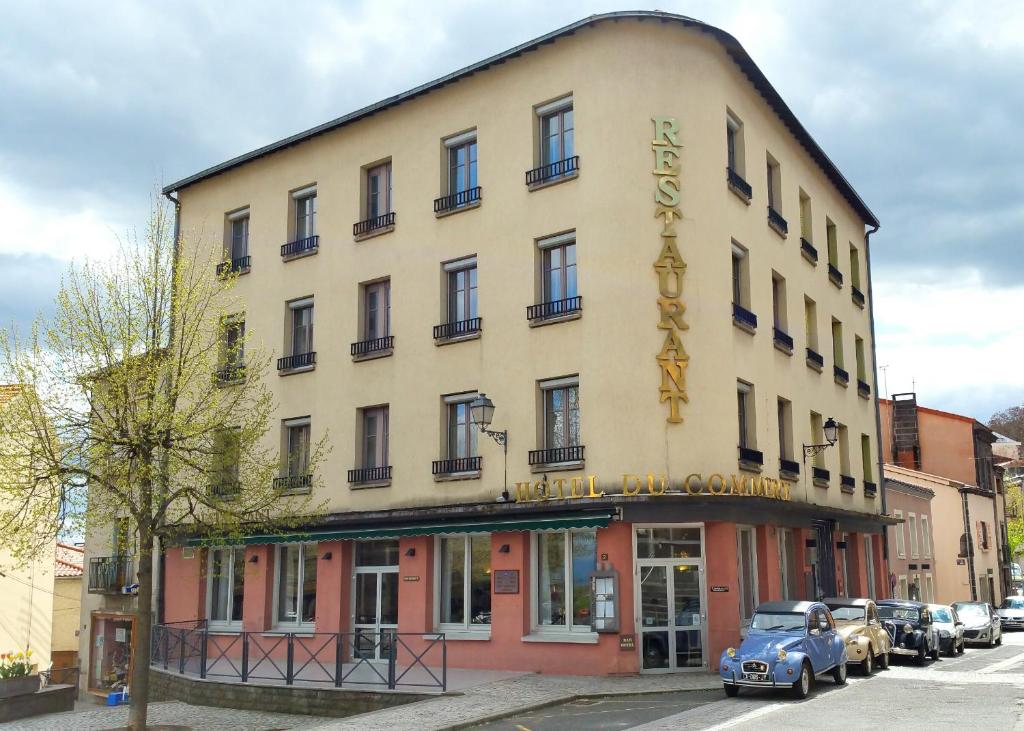 Un bâtiment avec une voiture bleue garée devant. dans l'établissement Logis Hôtel du Commerce, à Volvic