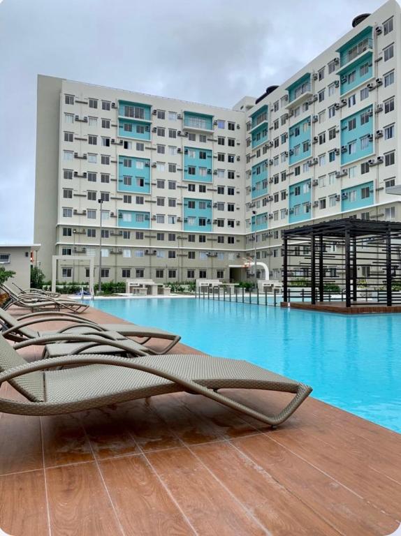 a swimming pool with lounge chairs in front of a building at Bienvenida Condotel in Dumaguete