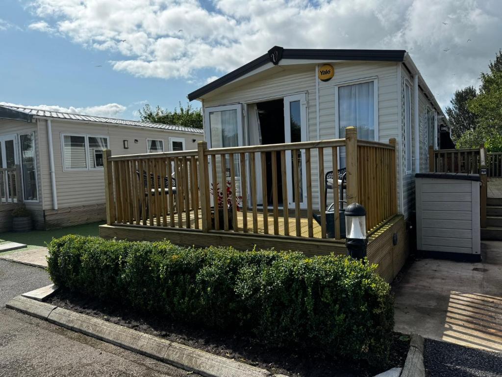 a small house with a large wooden deck at Hesket Caravan Park PLOT 42 3 pm check in Can sleep 6 with bed settee No commercial vans allowed in Carlisle