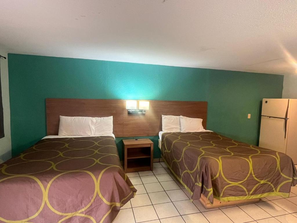 a hotel room with two beds and a green wall at Sun Motel in San Antonio