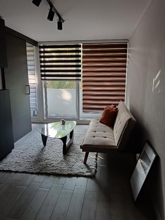 a living room with a couch and a glass table at Departamento Rondizzoni cercano a Movistar Arena y a 2 minutos del metro in Santiago