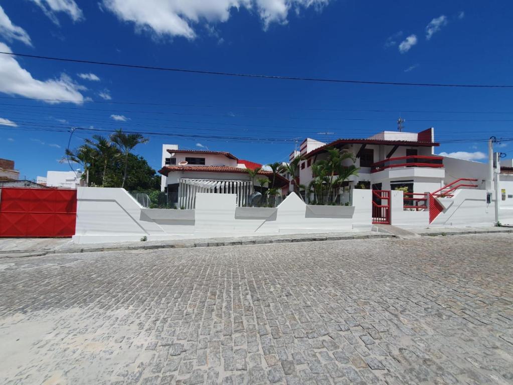 a white house with a red door on a street at Hotel raizes in Conceição do Coité