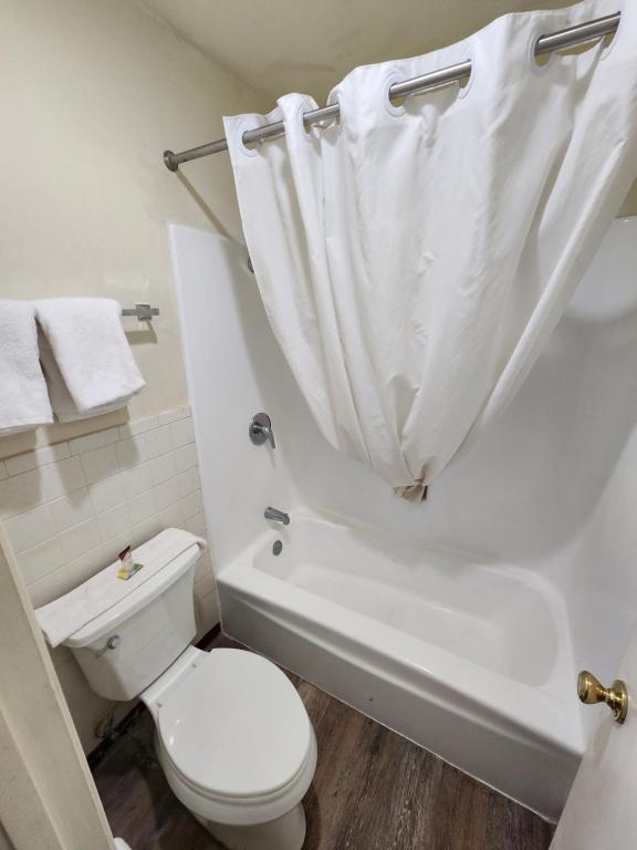 a bathroom with a toilet and a bath tub with a shower curtain at Satellite Inn in Alamogordo