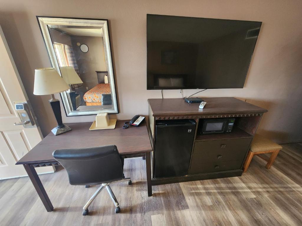 a desk with a mirror and a chair in a hotel room at Satellite Inn in Alamogordo