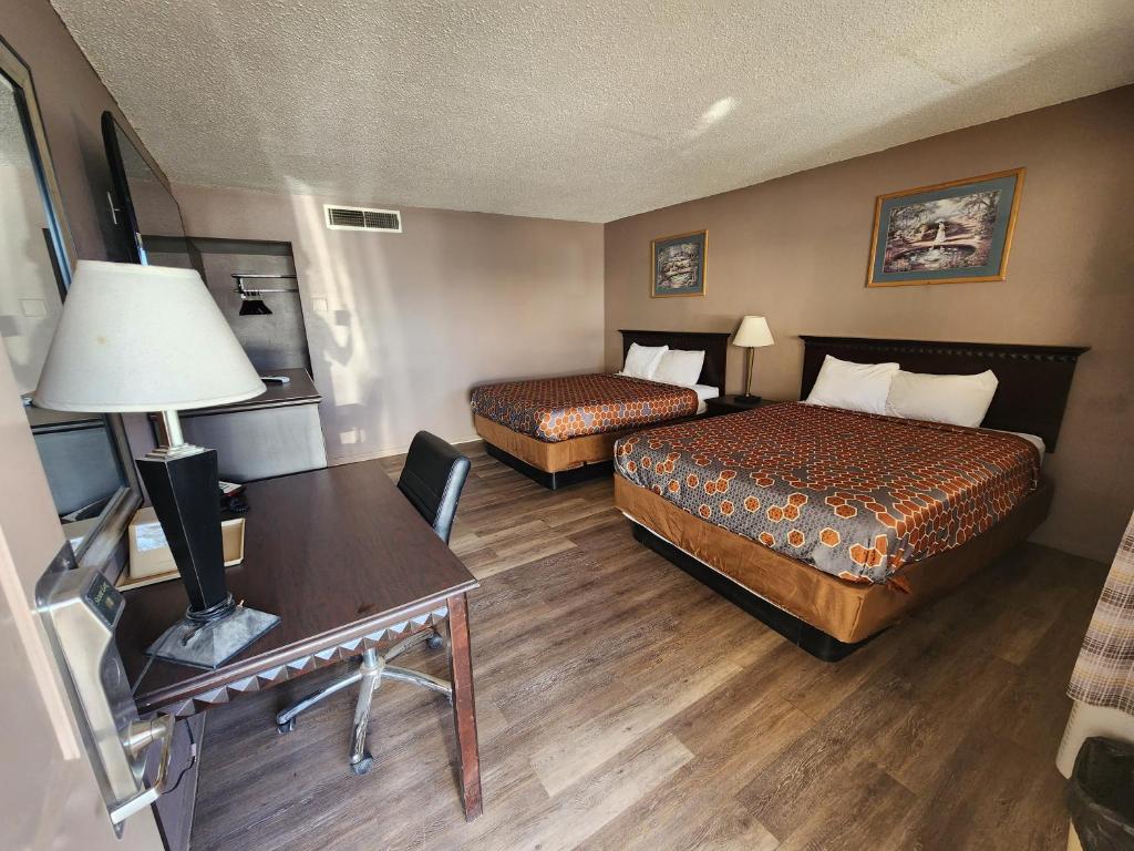 a hotel room with two beds and a desk at Satellite Inn in Alamogordo