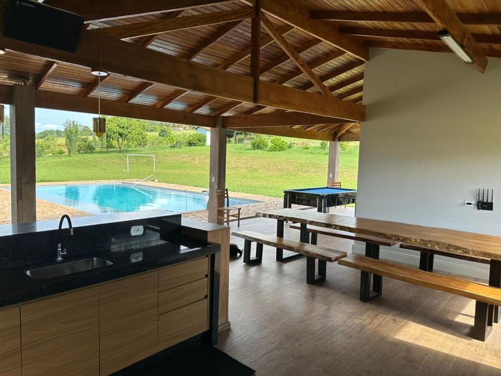 a kitchen with a table and benches and a pool at Sitio DusCosso in Bofete
