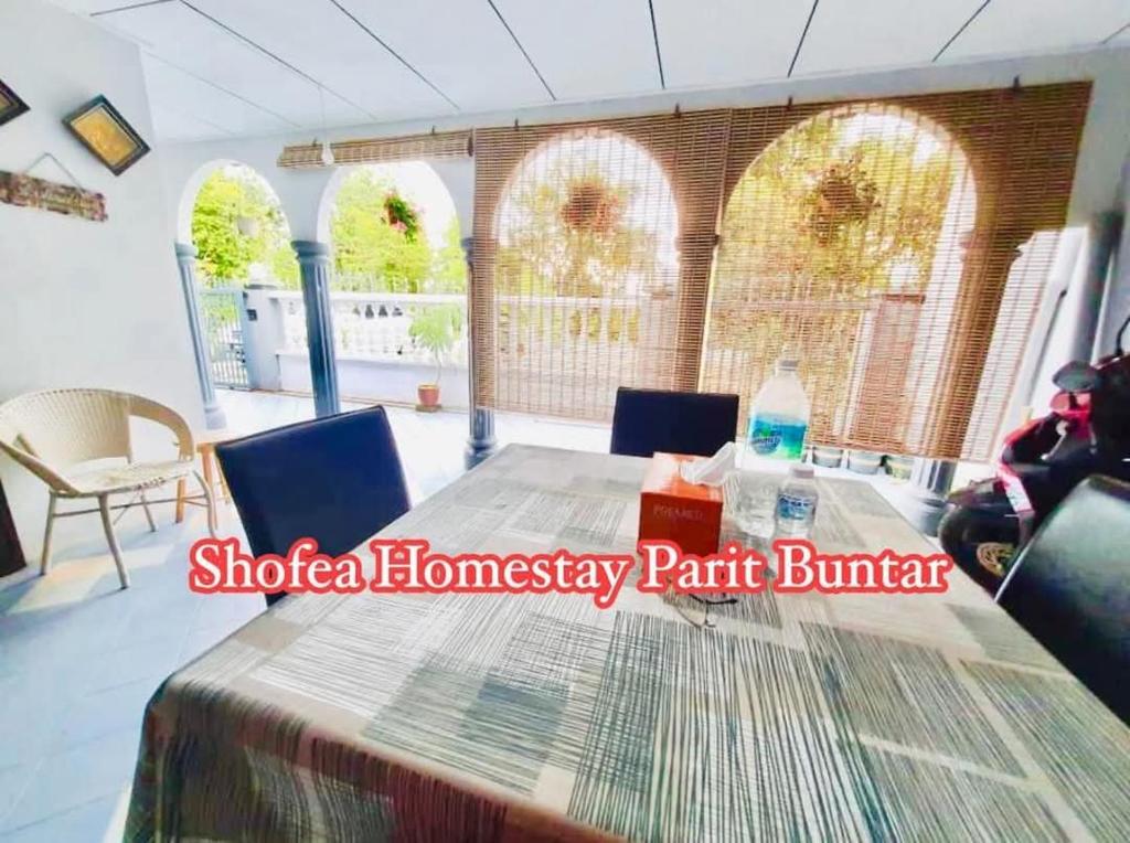 a room with a table and chairs and windows at Homestay Murah Parit Buntar in Parit Buntar