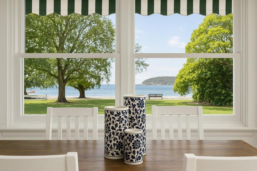 a dining room with two vases on a table in front of a window at Balmoral beauty - Elevated living on the esplanade BALO1 in Sydney