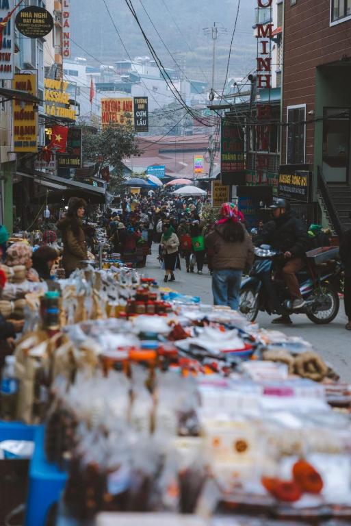 a group of people walking down a street with a market at Mountain Sprout Homestay in Dồng Văn