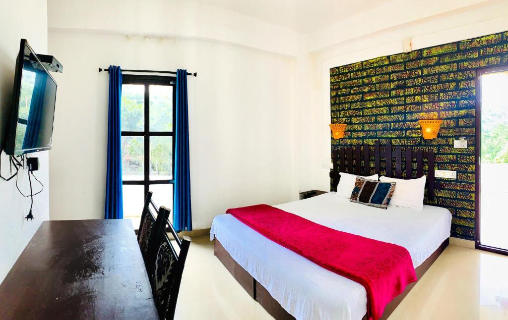 a bedroom with a bed with a red blanket and a desk at Restinn Homestay in Thekkady