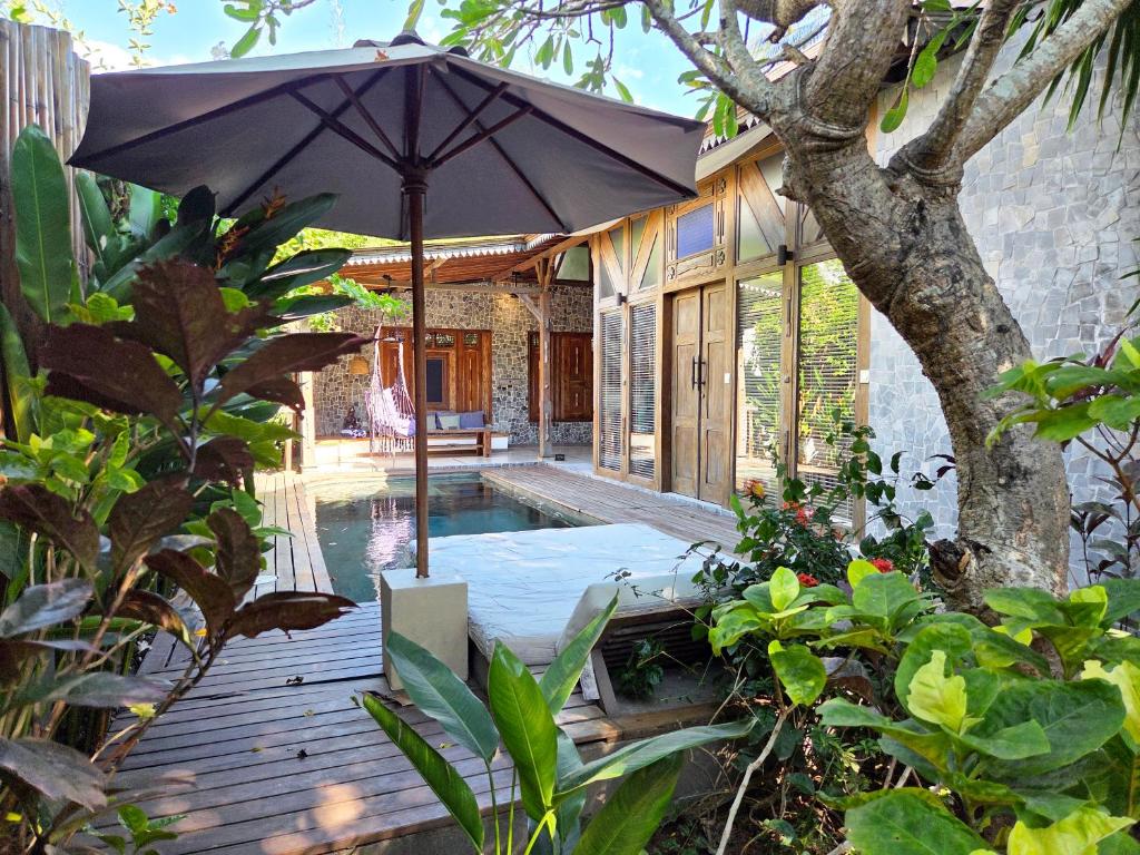 a patio with an umbrella and a swimming pool at Samsara Villas in Gili Islands