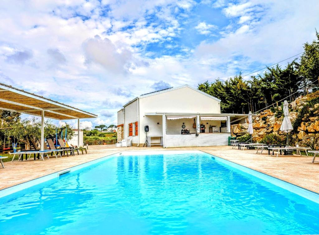 una piscina di fronte a una casa con un edificio di CI VULIA b&b - Sicilia sea, pool, bbq, tv, wi-fi ad Alcamo Marina