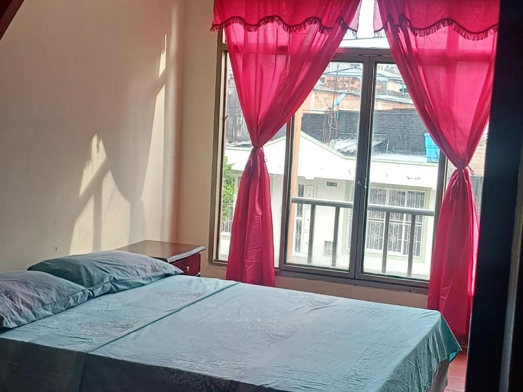 Schlafzimmer mit einem Bett und einem Fenster mit rosa Vorhängen in der Unterkunft habitación doble con parqueadero in Armenia