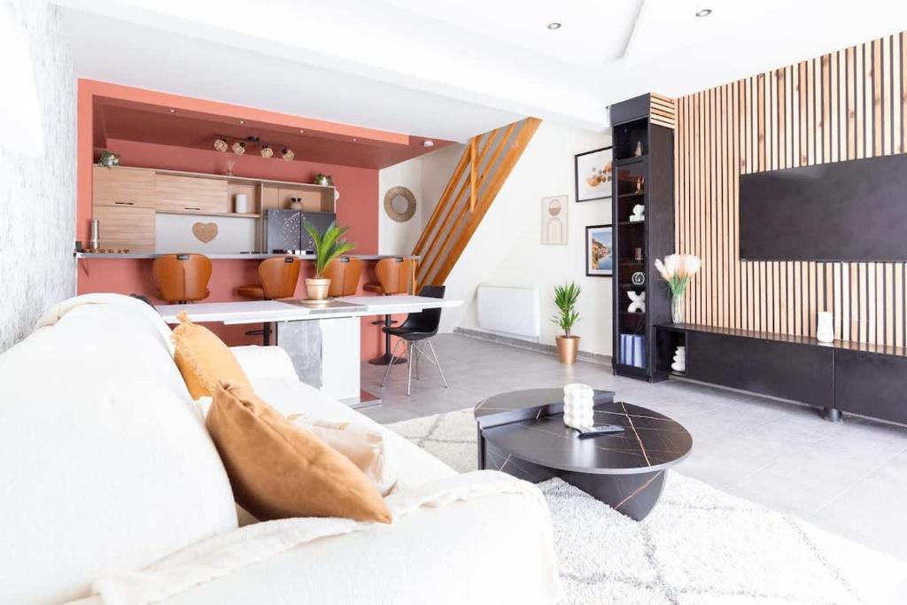 un salon avec un canapé blanc et une télévision dans l'établissement Loft tout confort avec parking et à moins 15 min Caen et des Plages, à Démouville