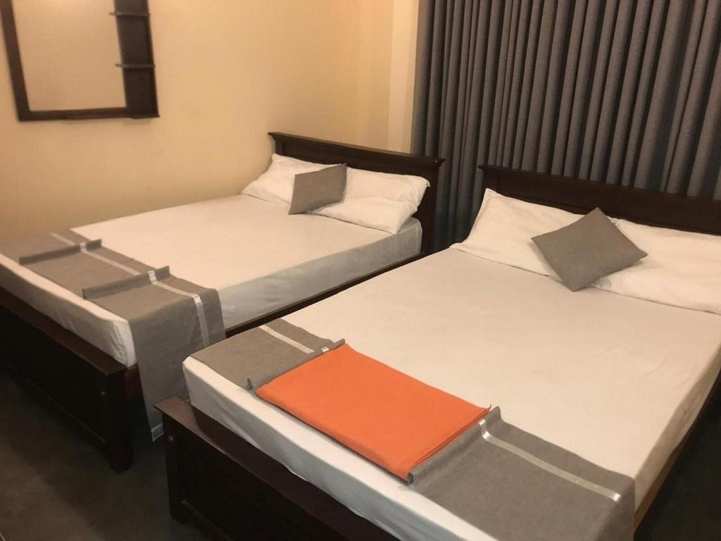 two beds in a hotel room with an orange folder at UDF City Hotel in Kandy
