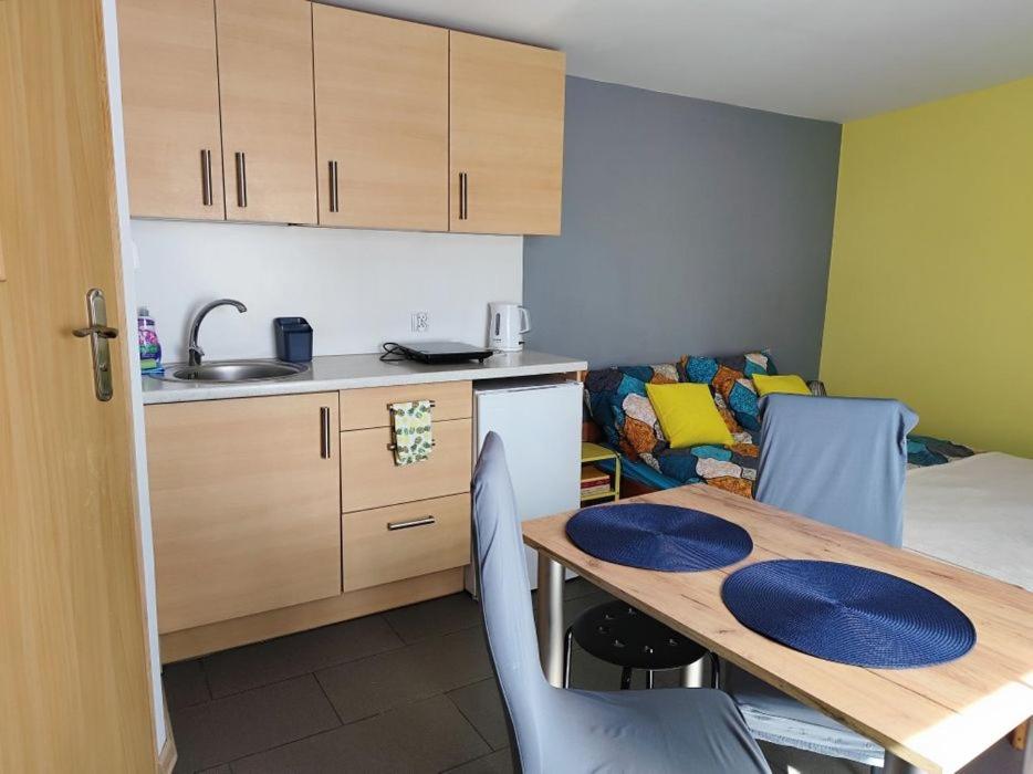 a kitchen with a wooden table and a kitchen with a couch at Domek dla dwojga w Stegnie in Stegna