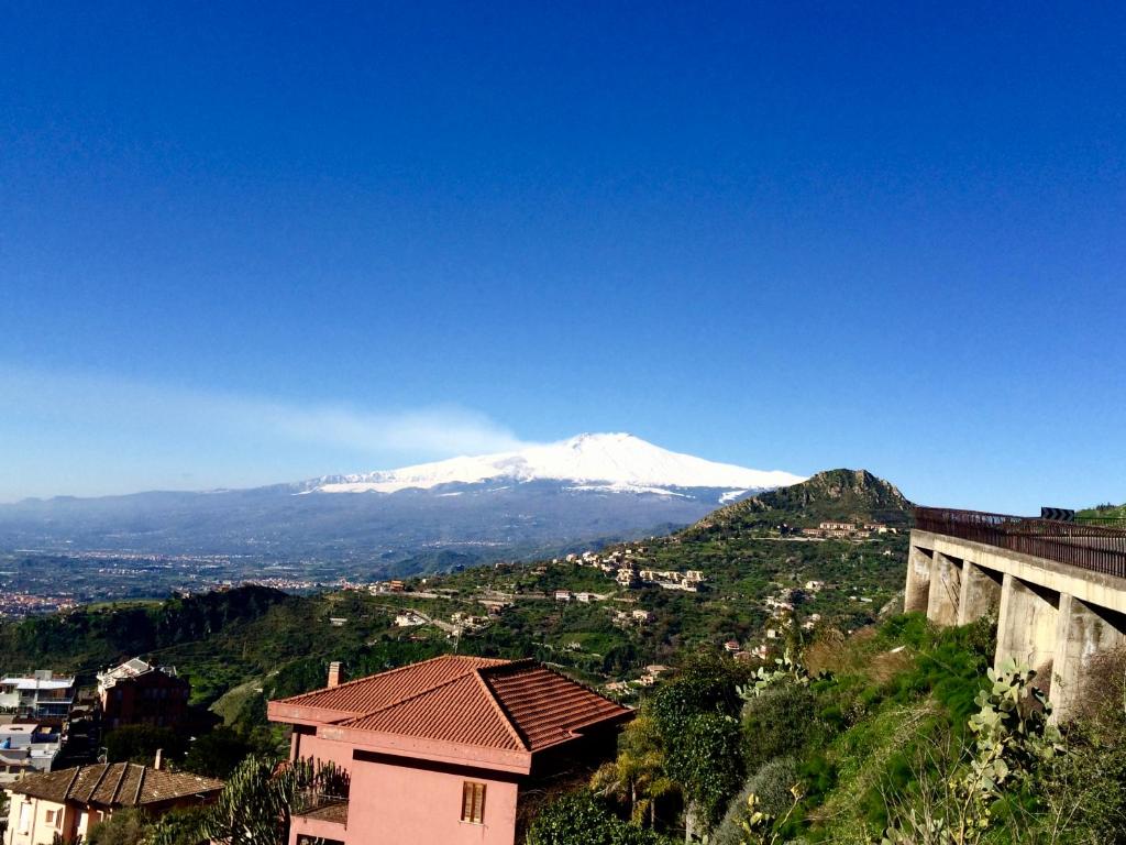 uma montanha coberta de neve à distância com um edifício em Villa Quisisana Taormina em Taormina