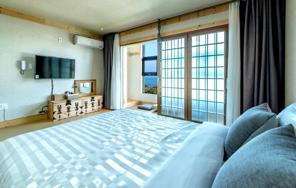 a bedroom with a large bed and a large window at Bada Maru Pension in Seogwipo