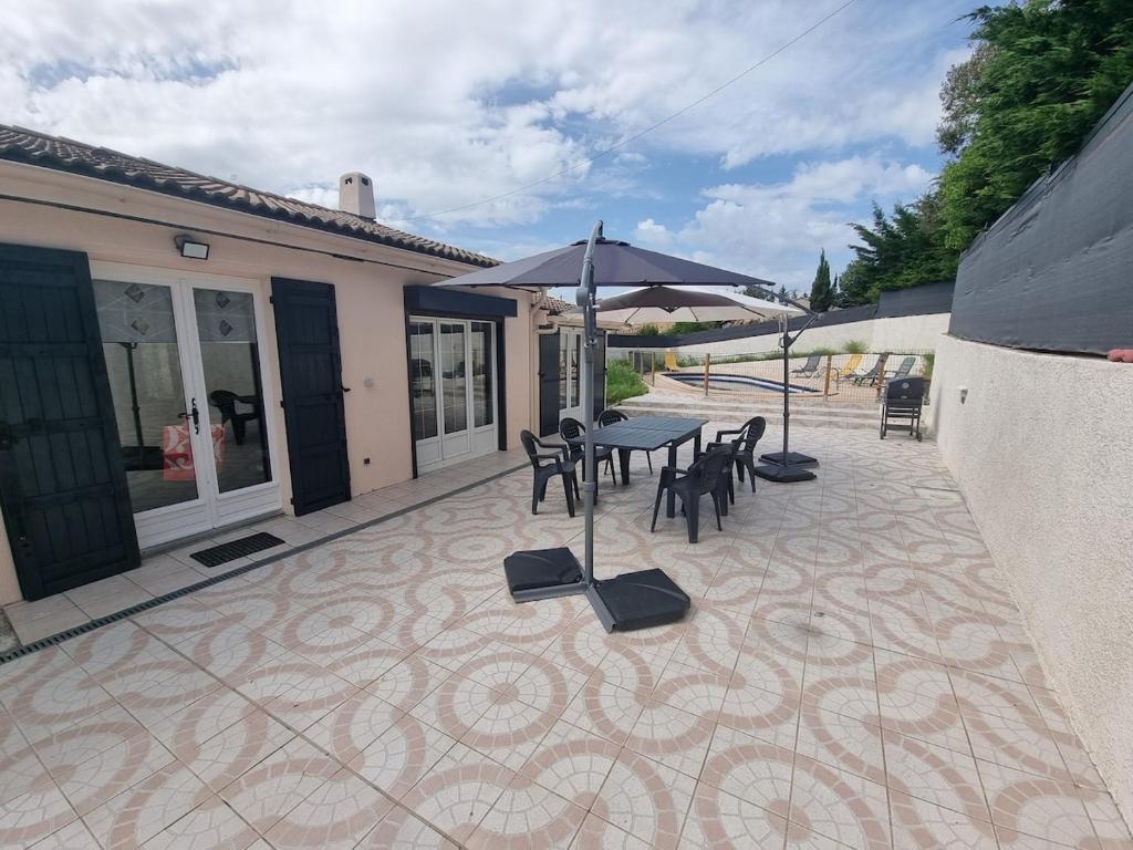 un patio avec une table, des chaises et un parasol dans l'établissement Villa avec piscine, à Rocbaron