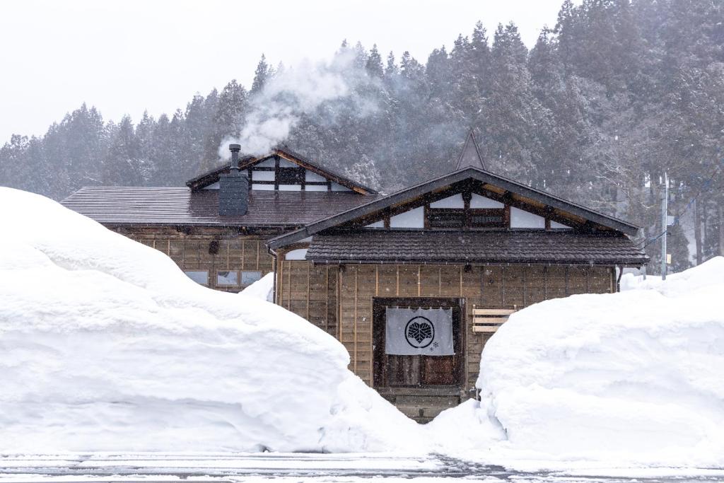 a house covered in snow with trees in the background at 雪の家 古澤邸 in Tokamachi