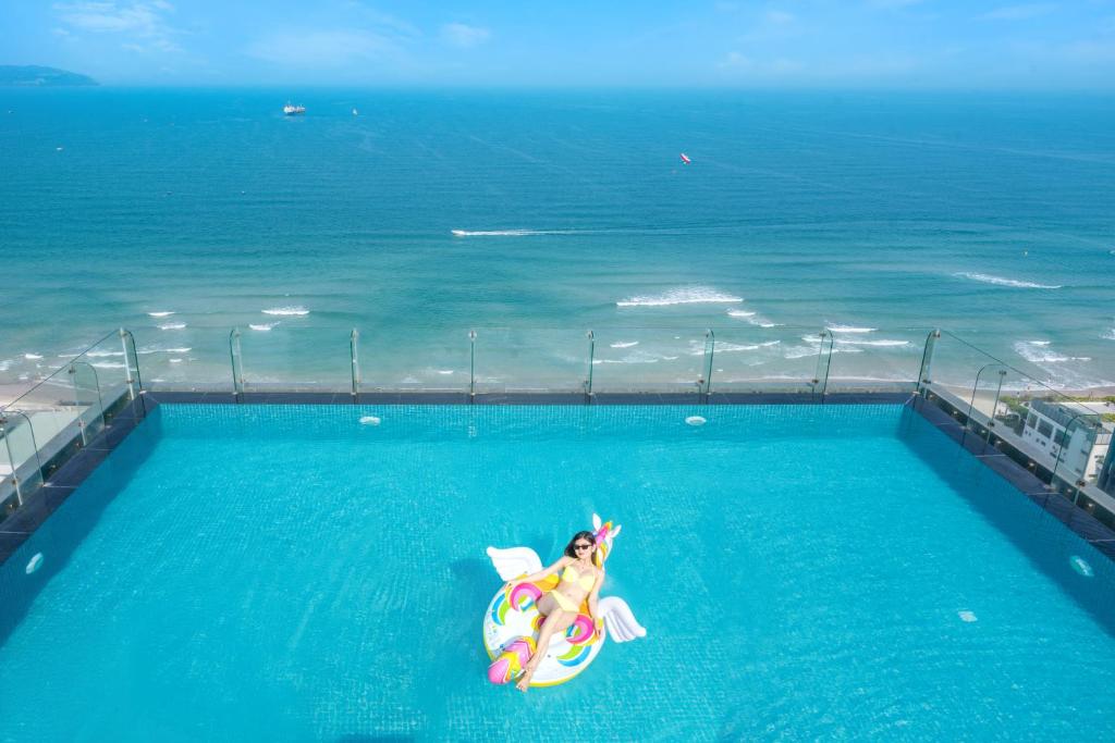 a woman laying on an inflatable at Canvas Danang Beach Hotel in Danang