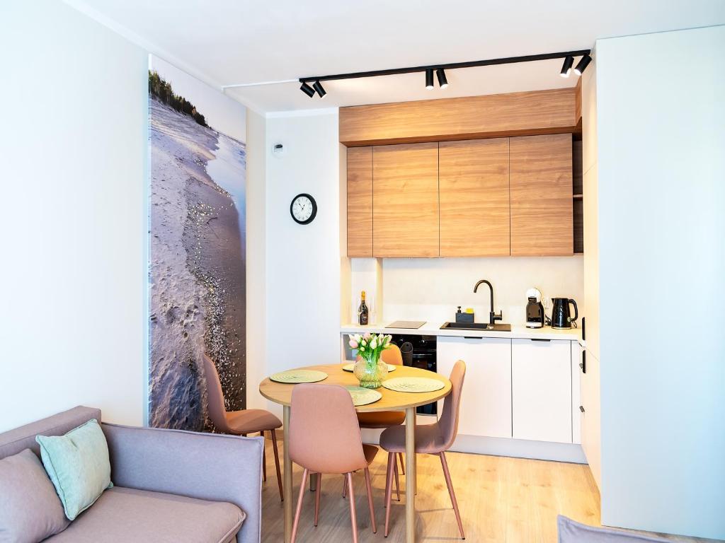 a kitchen and living room with a table and chairs at MomUla's Apartment Pino Sobieszewo Gdańsk in Gdańsk