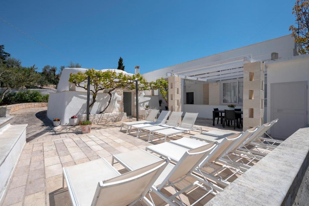 eine Gruppe weißer Stühle und ein Tisch auf einer Terrasse in der Unterkunft Trullo Cecé in Ostuni