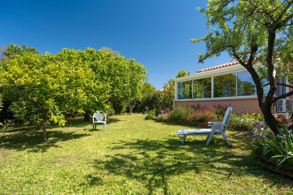 einen Park mit zwei Stühlen und einer Bank im Gras in der Unterkunft Jolie Maison Proche De La Plage in La Londe-les-Maures