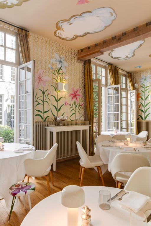 een restaurant met tafels en stoelen en bloemen aan de muur bij Small Luxury Hotel De Witte Lelie in Antwerpen