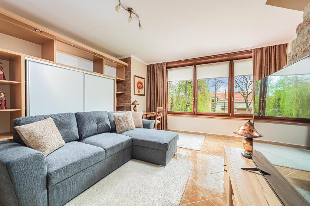 a living room with a couch and a large window at Komló Apartman - Gyula in Gyula