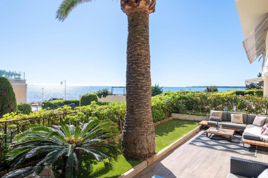 une terrasse avec un palmier, une table et des chaises dans l'établissement 3-Br Apartment with Private Pool & Sea View, à Cannes